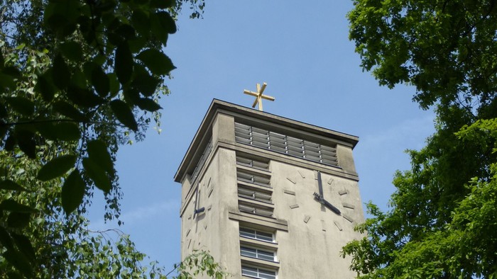 Der Turm einer Kirche ragt zwischen Bäumen empor