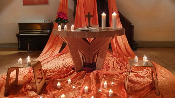 Ein Altar in einer Kirche mit Kerzen und roten Tüchern geschmückt