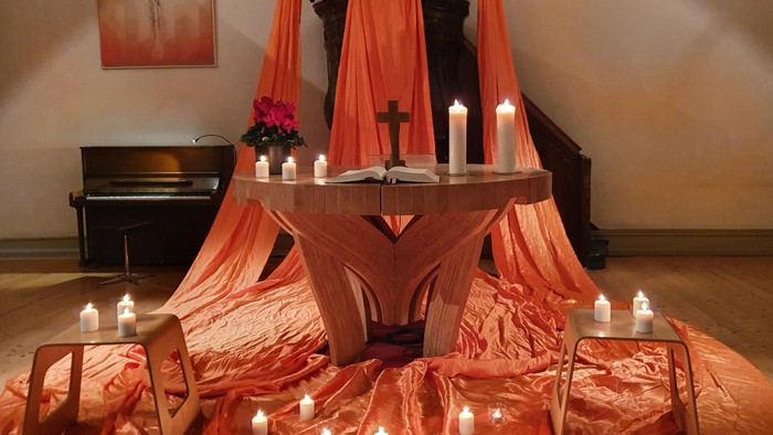 Ein Altar in einer Kirche mit Kerzen und roten Tüchern geschmückt
