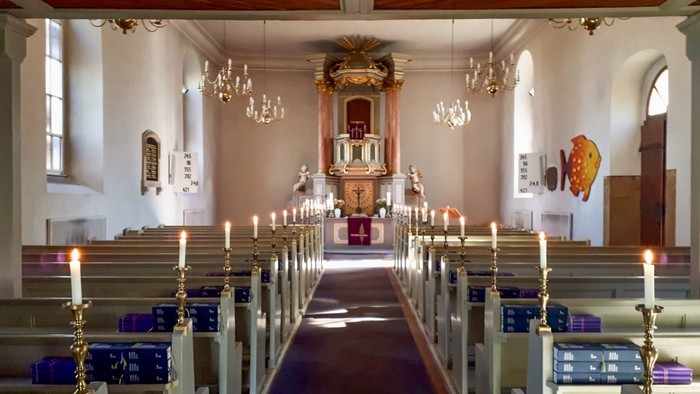 Blick auf den Altarraum in der Dorfkirche Lübars mit angezündeten Kerzen