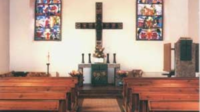 Kirchlicher Innenraum mit Kreuz und Buntglasfenstern
