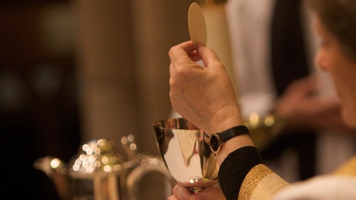 A person holding a small circular object near a teapot.