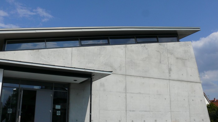 Modernes Gebäude mit flacher Überdachung und großen Glasfenstern