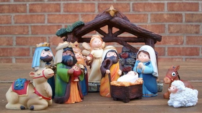 Nativity scene with figures and animals displayed on wooden table.
