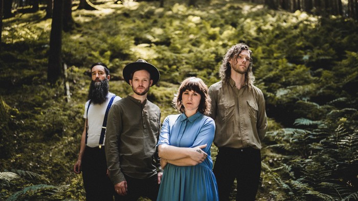 Fire personer står sammen i en skov.