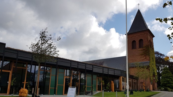 Et moderne kirkebygning med glasfacader og en tårn med spids tak.