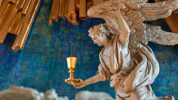 En engelstatue med vinger og en kelch i hånden.