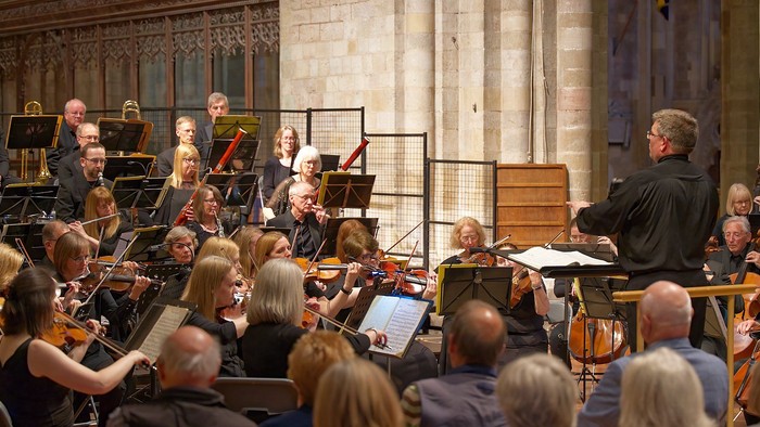 Orchestra performing in grand hall with audience.