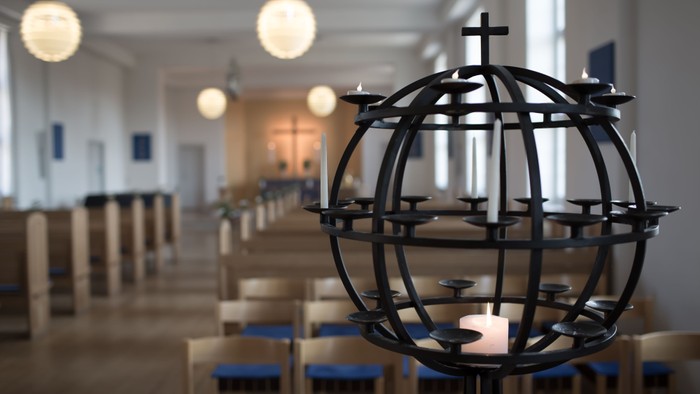 En globus med lysestage i kirke med blå stoler og hængende lygter