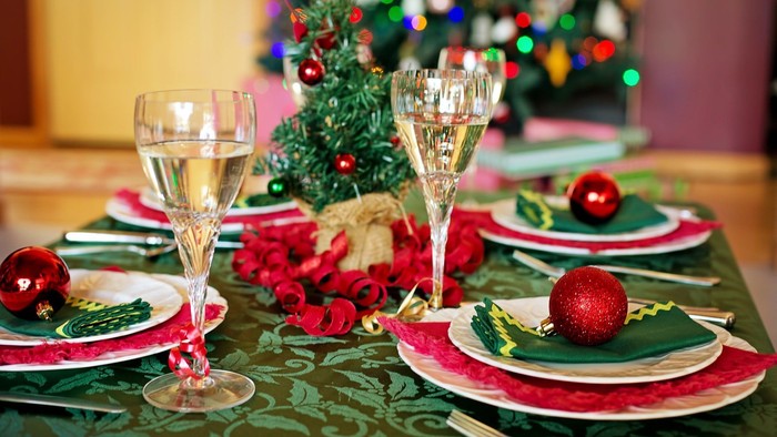 En festligt jul-inspiret bord med røde og grønne dekorationer, glas, og belysning