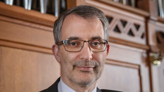 Mand i formel klædning sidder ved orgel.