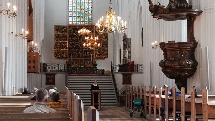 Indenrig af en stor kirke med høje vægge og bænke.