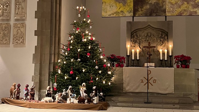 In der Kirche steht ein geschmückter Weihnachtsbaum vor dem Altar.