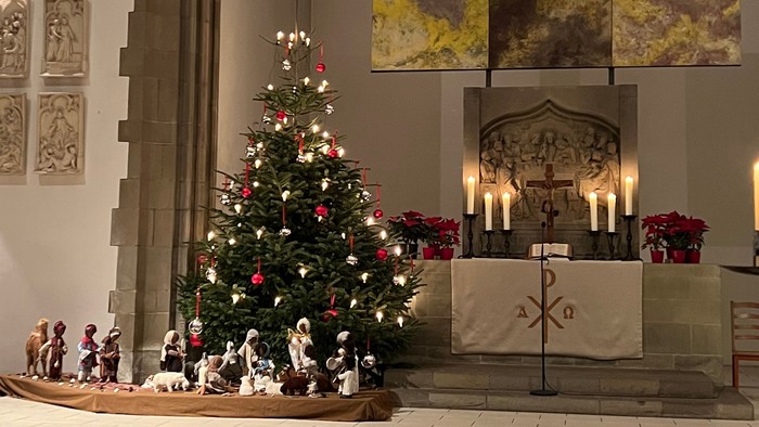In der Kirche steht ein geschmückter Weihnachtsbaum vor dem Altar.
