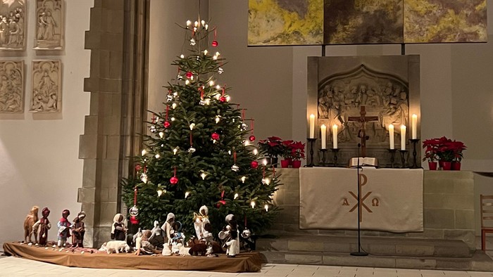 In der Kirche steht ein geschmückter Weihnachtsbaum vor dem Altar.