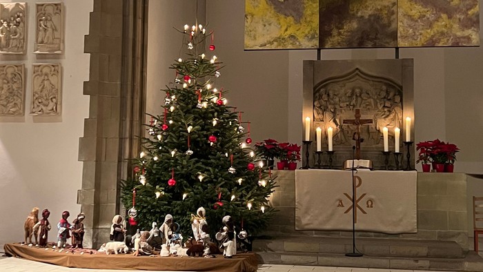 In der Kirche steht ein geschmückter Weihnachtsbaum vor dem Altar.