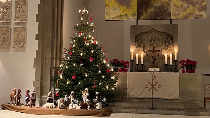 In der Kirche steht ein geschmückter Weihnachtsbaum vor dem Altar.
