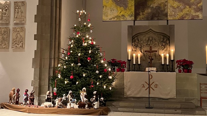 In der Kirche steht ein geschmückter Weihnachtsbaum vor dem Altar.