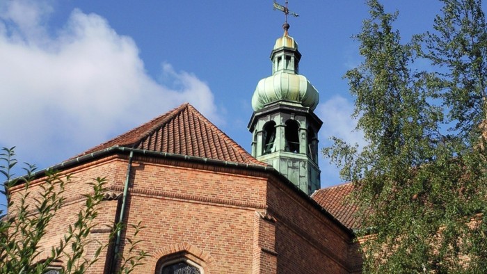 En rød murstenskirke med grøn tårn og guldstjern.