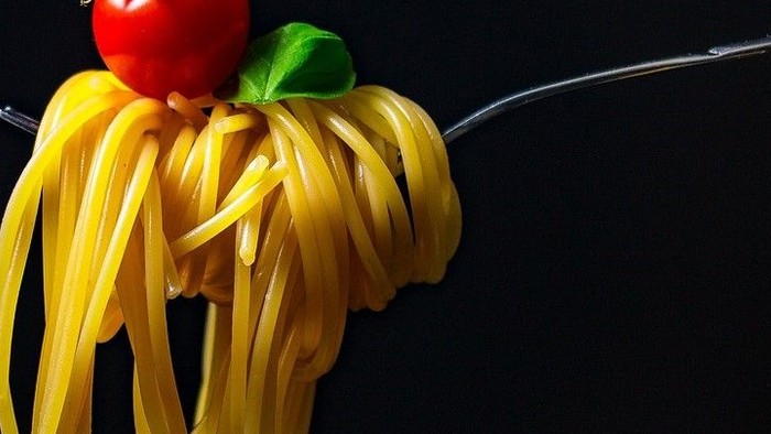 En gabel med spaghetti og tomat.