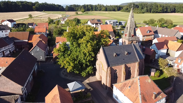 Dorf mit Kirche und umgebender Landschaft