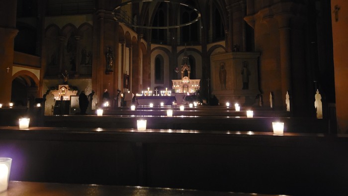 Kircheninneres mit brennenden Kerzen und religiösen Statuen.