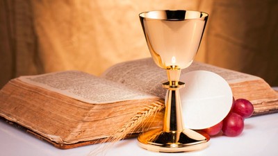 Golden chalice beside open book and grapes