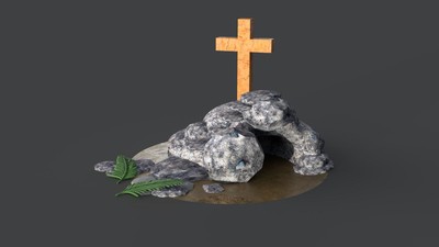 A wooden cross rests on top of a pile of rocks with a green leaf nearby.