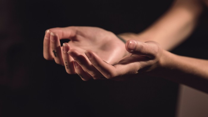Two hands gently touching, one palm facing up, the other resting on top.