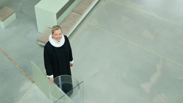 To tre kvinder i et moderne indretning med store vinduer og glassejler.