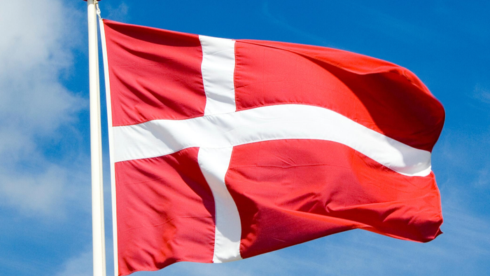Dansk flag waver i bløgt blå himmel.