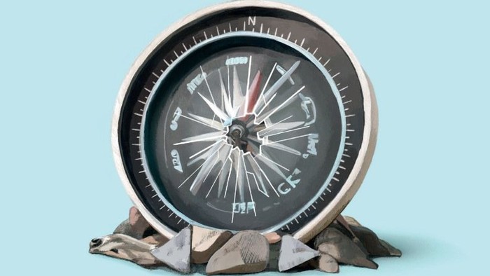 Ein Kompass auf einem Felsen vor blauem Hintergrund