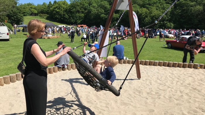En kvinde trækker et barn op i en sandboks på en fest.