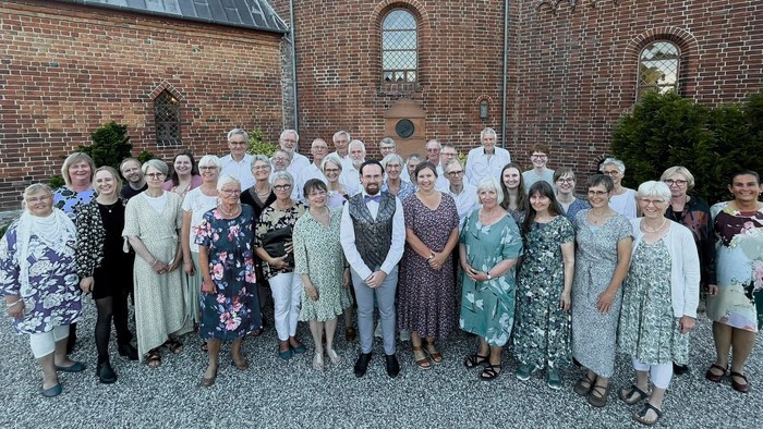 En gruppe af mennesker står sammen udenfor en murstensbygning