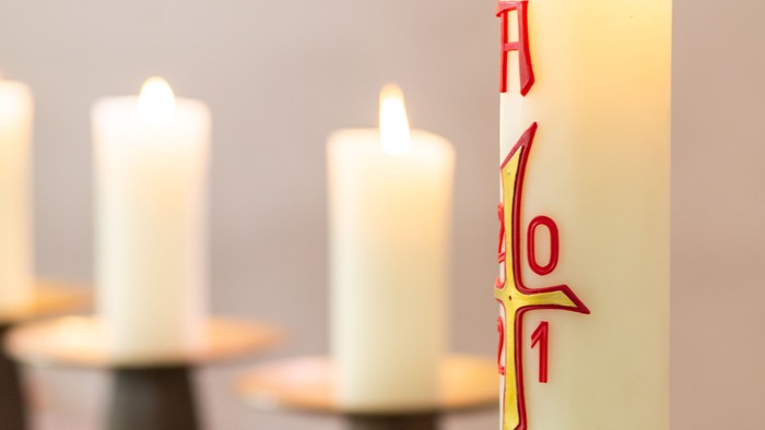 Weiße Kerzen, eine mit roter Schrift, stehen auf einem Tisch