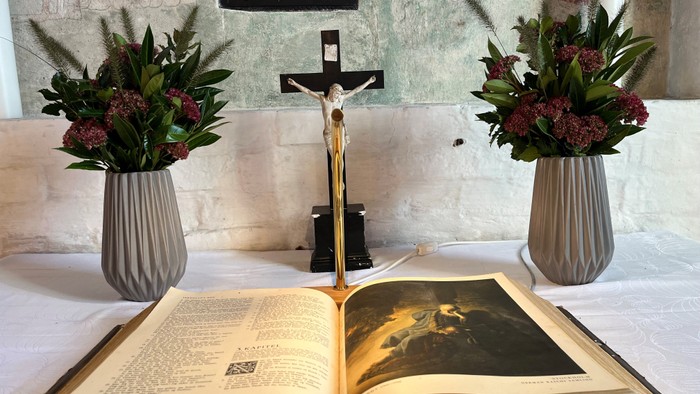 To altertabel med blomsterarrangementer og åben bog