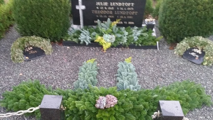 Gravsted med grønne planter og gravstene med blomster.