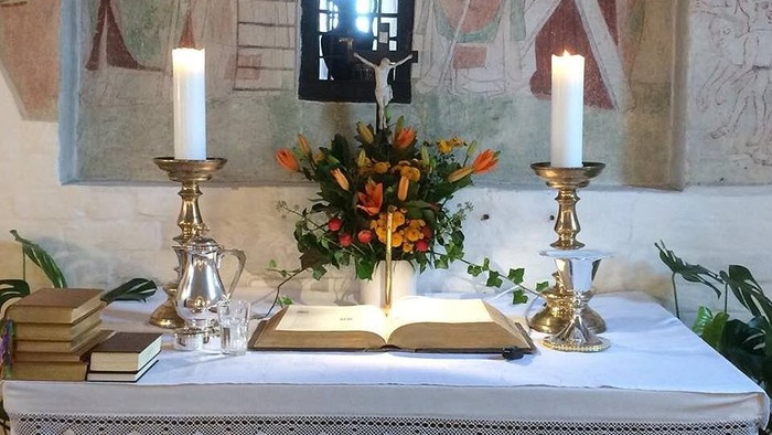 Altaret i kirken med lysestake, blomster og bibler