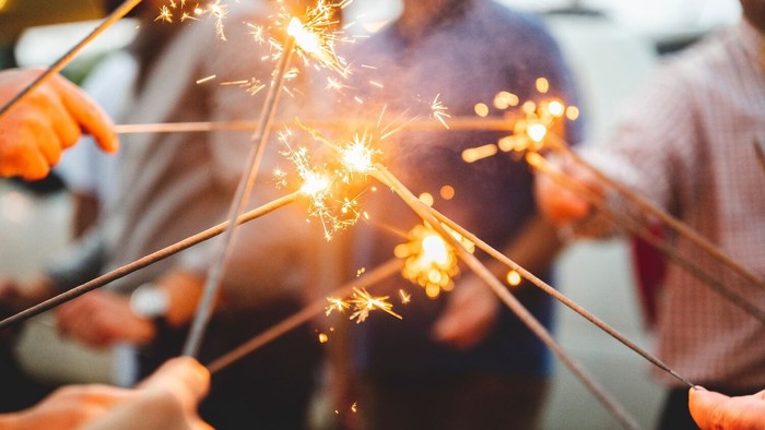 Menschen halten Raketen, die Funken sprühen