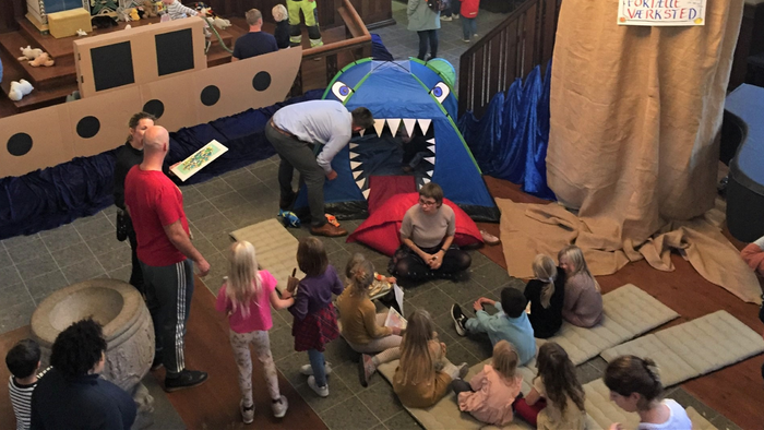 Børn spiller i et skib og en drake i kirkehal.