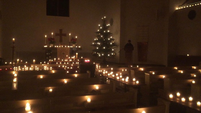 Kirchliche Innenansicht mit zahlreichen brennenden Kerzen und Weihnachtsbaum