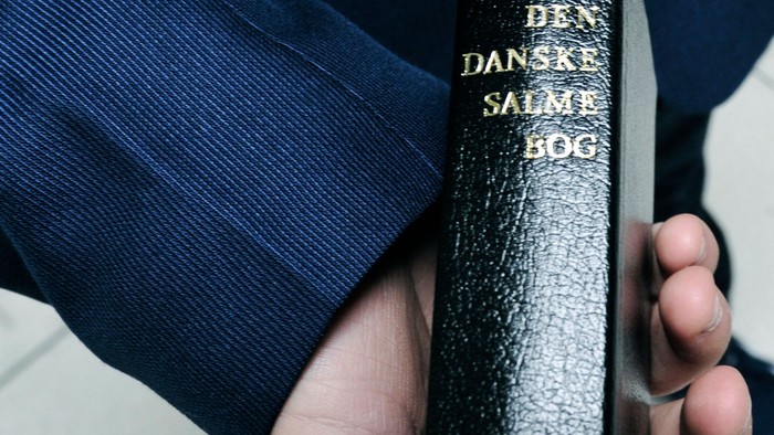 Person holder en sort bog med guldskrift.