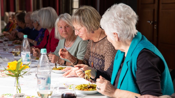 Eine Gruppe älterer Frauen sitzt bei einem gemeinsamen Essen an einem Tisch.