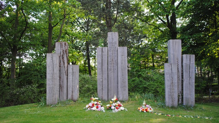 Im Park stehen mehrere hohe Steinsäulen mit Blumenarrangements davor.
