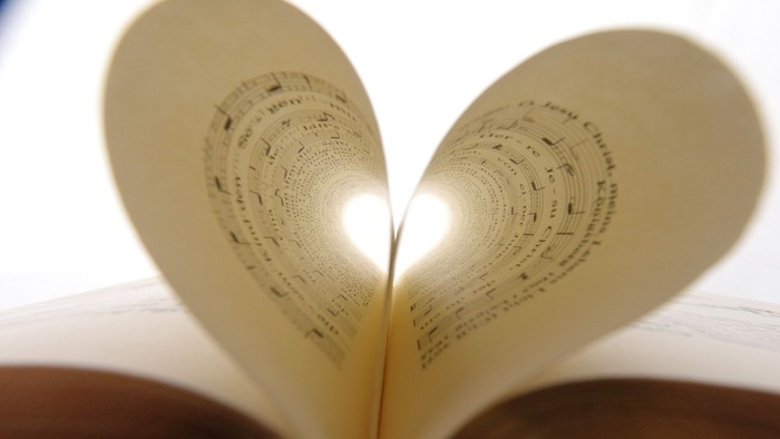 Ein Gesangbuch liegt aufgeschlagen da. Zwei Seiten in der Buchmitte sind zu einem Herz geformt.