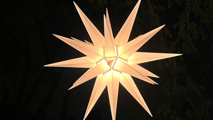 Vor dunklem Hintergrund leuchtet ein Herrnhuter Stern.