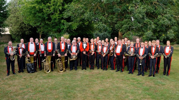 Group of musicians posing outdoors with instruments.