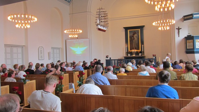 En kirke med en stor samling af mennesker, lys og et skilt med et skib.