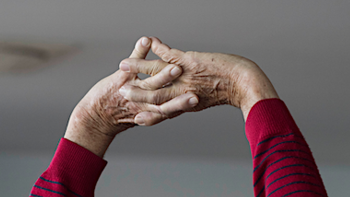 Alte Hände in rotem Pullover verschränkt