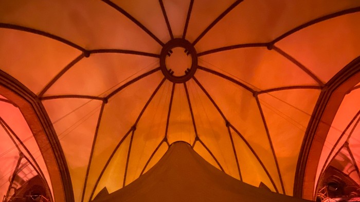 Großer Ballsaal mit hohem, verziertem Dach und Menschen im Vordergrund